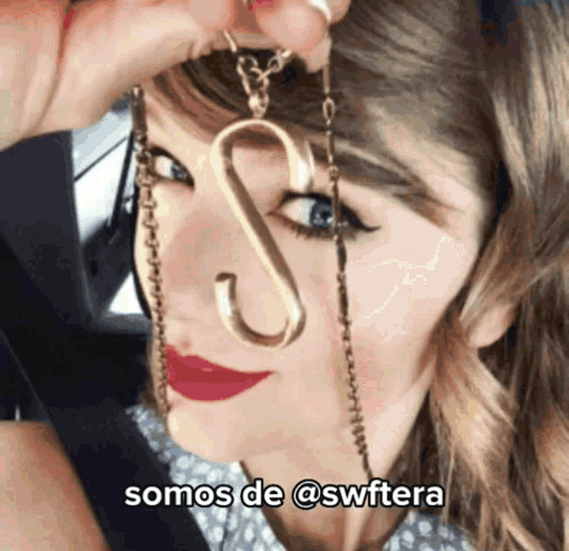 a woman is holding a necklace with the letter s