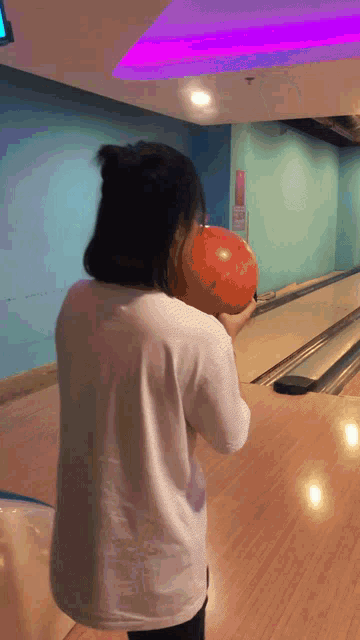 a girl in a white shirt is holding a bowling ball in her hand