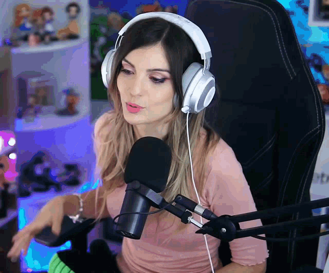 a woman wearing headphones sits in front of a mic