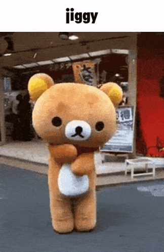 a teddy bear is standing in front of a building with the word jiggy above it