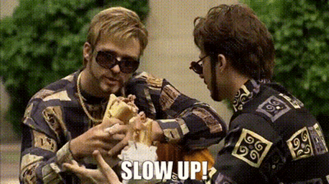 two men are eating a sandwich and the words slow up are on the screen