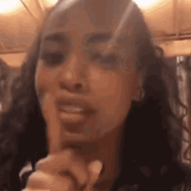 a close up of a woman 's face with her finger to her mouth .