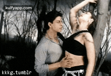 a man is touching a woman 's stomach in a forest .