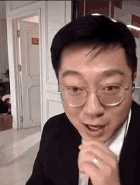 a man wearing glasses and a suit is making a face .