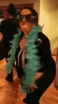 a woman is wearing sunglasses and a green boa while dancing .