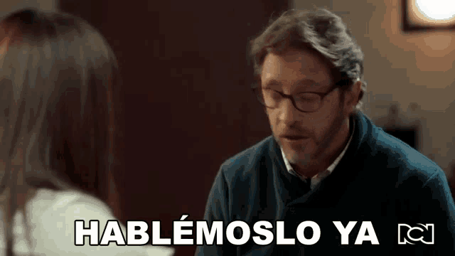 a man with glasses is talking to a woman with the words hablamoslo ya in the corner