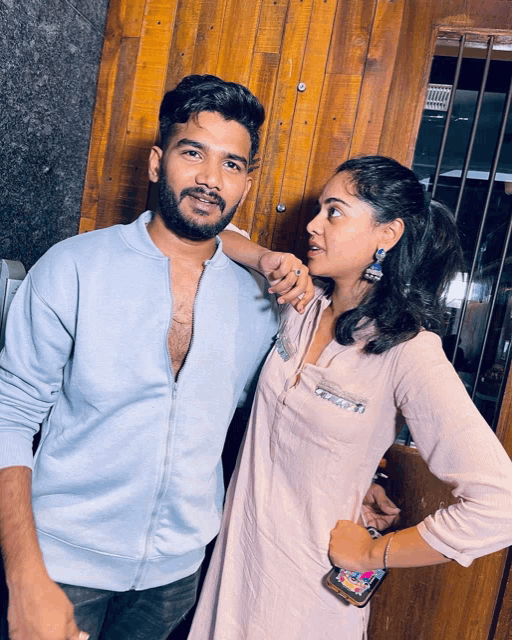 a man and a woman are posing for a picture and the woman is wearing earrings