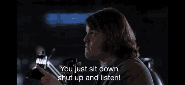 a man says " you just sit down shut up and listen " in a dark room