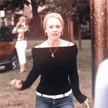 a woman wearing a black off the shoulder top with a letter r on it
