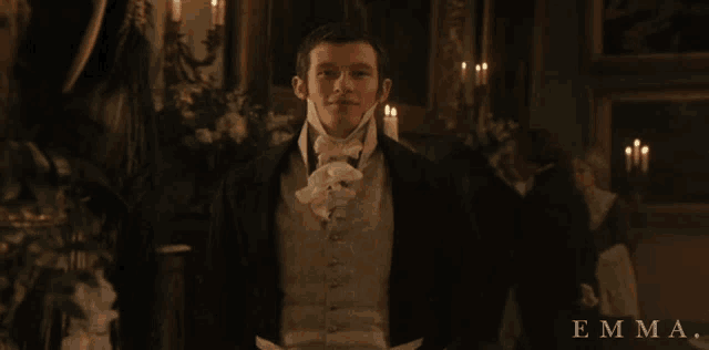 a man in a tuxedo is standing in a room with the name emma on the bottom