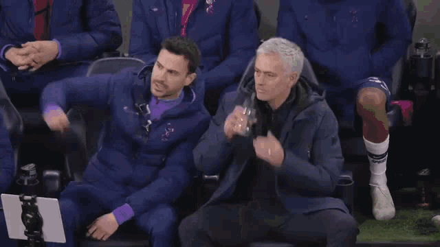 two men are standing on a soccer field talking to each other .