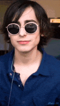 a young man wearing sunglasses and a blue shirt with mary c3 written on the collar