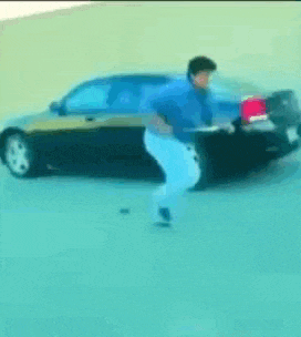 a man in a blue shirt is pushing a car