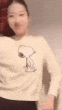 a woman wearing a white sweater with snoopy on it is dancing .