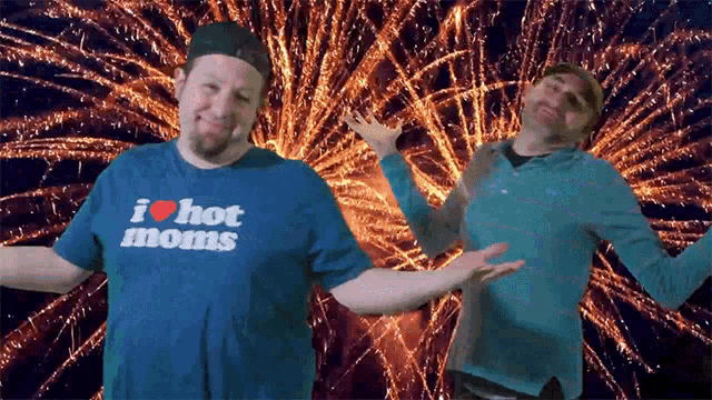 a man wearing a shirt that says i heart hot moms stands in front of fireworks