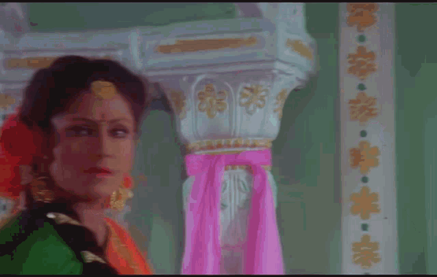a woman in a green and orange dress is standing in front of a wall