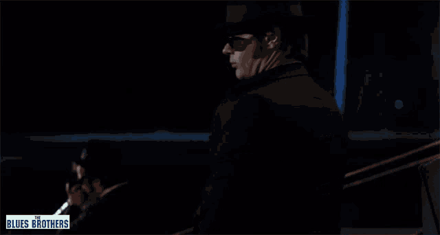 a man in a suit and tie is pointing to his chest with the words blues brothers on the bottom
