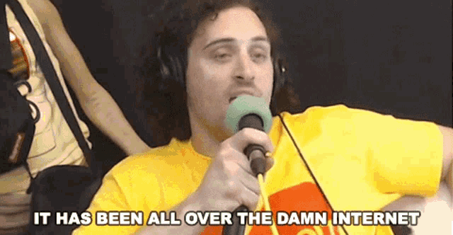 a man wearing headphones is holding a microphone and saying it has been all over the damn internet