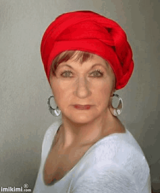 a woman wearing a red head scarf and earrings is looking at the camera .