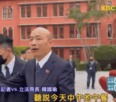 a man in a suit stands in front of a building with chinese writing