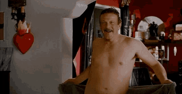 a shirtless man with a mustache is wrapped in a towel and smiling .