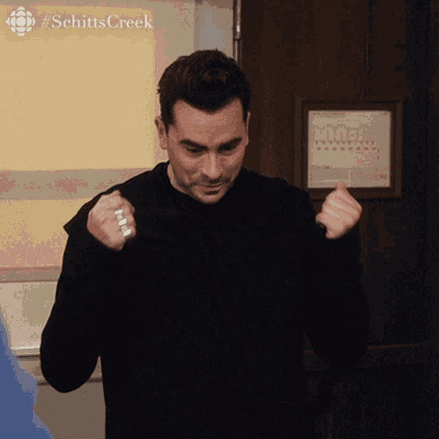 a man stands in front of a sign that says schittscreek