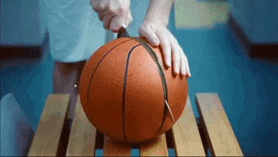 a person is cutting a basketball with a knife on a wooden bench