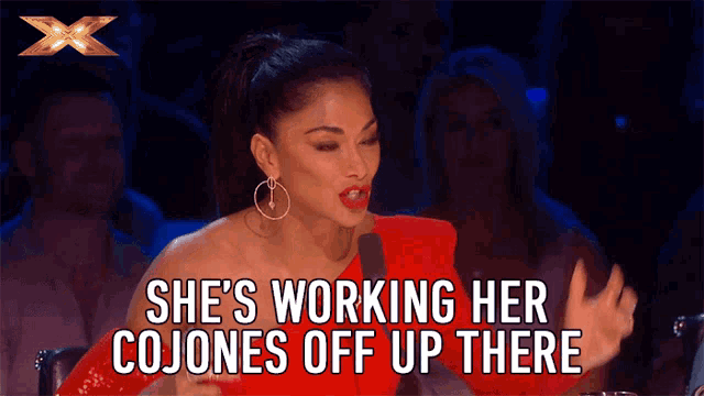 a woman sitting in front of a microphone with the words she 's working her cojones off up there above her