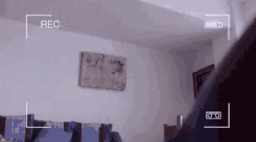 a person is standing in a living room with a rec button on the screen