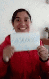 a woman in a red jacket is smiling and holding a sign that says " warning "