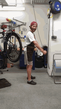 a man in a red hat stands in front of a bicycle in a garage