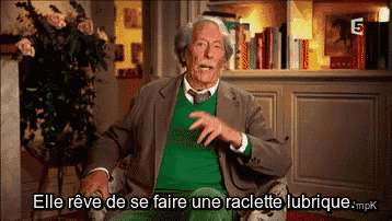 a man in a green sweater is sitting in a chair with the words elle reve de se faire une raclette lubrique