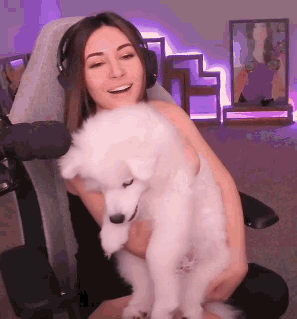 a woman is holding a small white dog in her arms