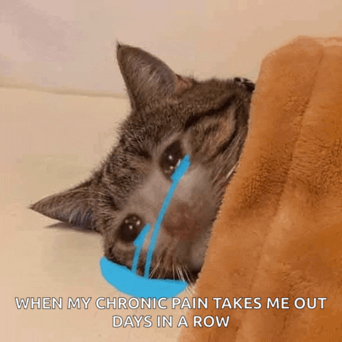 a cat is laying under a blanket with a blue tear coming out of its eye .