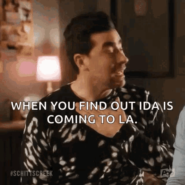 a man in a black and white polka dot sweater is talking to another man in a room .