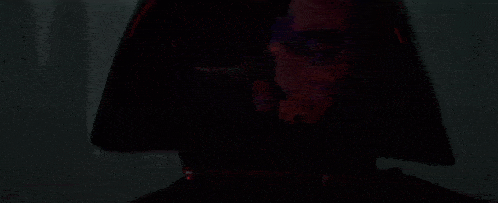 a close up of a person 's face in a dark room with a red light behind them .