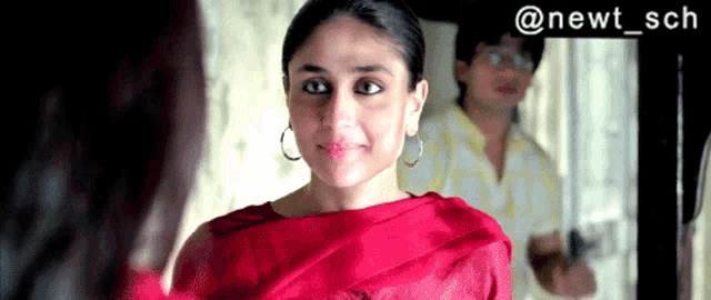 a woman in a red dress is looking at herself in a mirror .