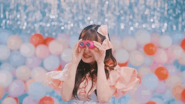 a girl in a pink dress is holding a pink object