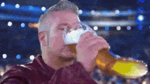 a man is drinking a beer from a glass while watching a game .