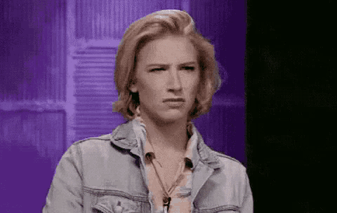 a woman wearing a denim jacket is making a funny face
