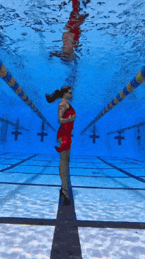 a woman in a red dress stands underwater in a swimming pool