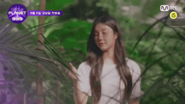 a girl in a white shirt is standing in front of a jungle with plants .