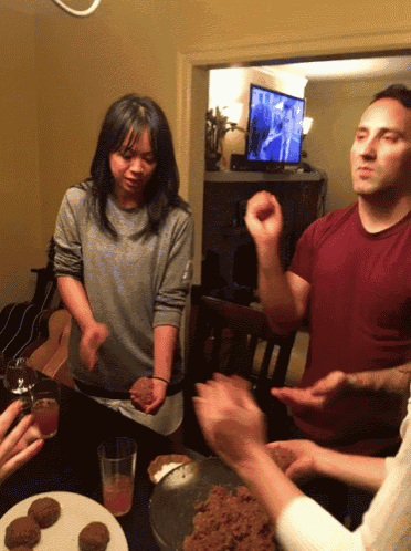 a group of people are gathered around a table with food and drinks