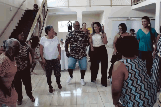 a group of people are dancing in a room with stairs