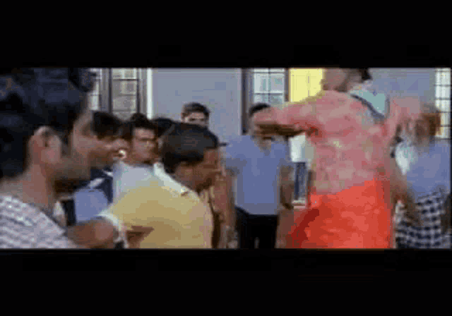 a group of people are standing around a man in a red shirt .