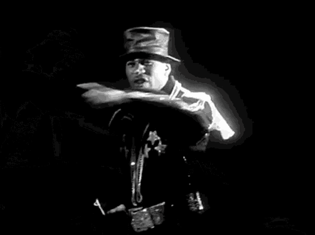a black and white photo of a man wearing a top hat and sunglasses .