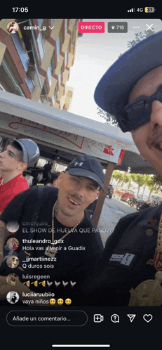 a man wearing a black hat and sunglasses is standing next to another man
