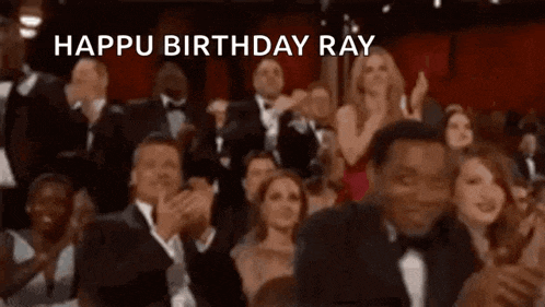 a crowd of people are clapping and applauding while a man in a tuxedo says happi birthday ray .