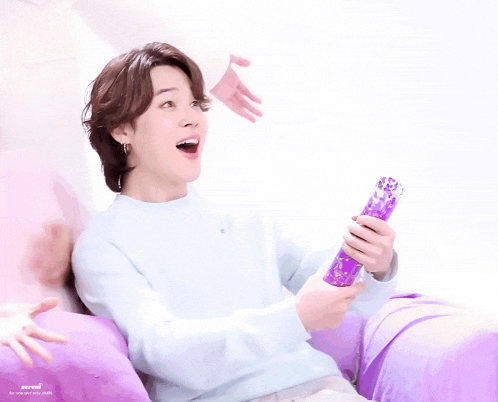 a person sitting on a purple couch holding a purple object with a surprised look on his face