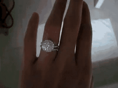 a close up of a woman 's hand with a diamond ring on it .
